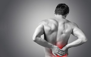 Man holding back who needs back pain treatment